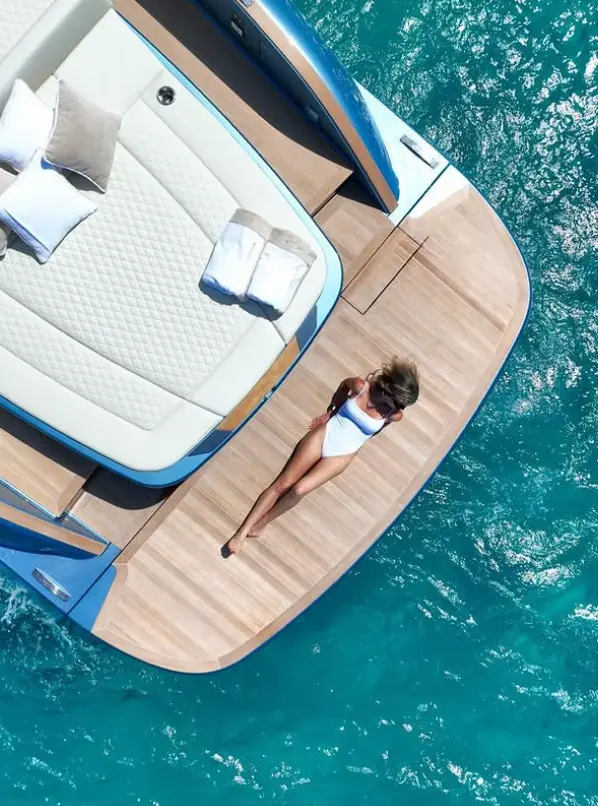 Vrouw in wit badpak ontspant op een luxe jacht in helderblauw tropisch water.
