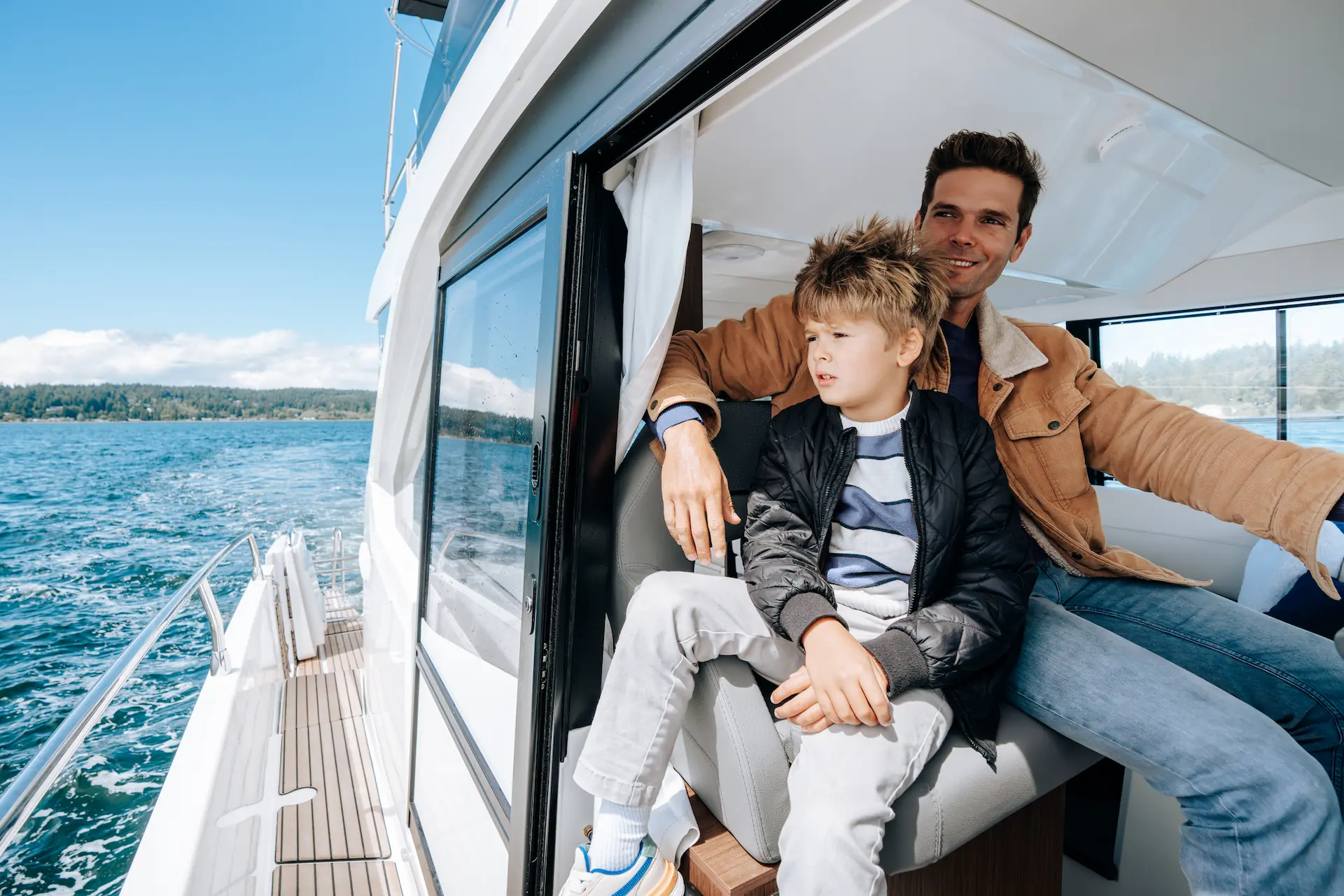 Vader en zoon genieten samen van een boottocht op het water aan boord van een Lomac Milano.