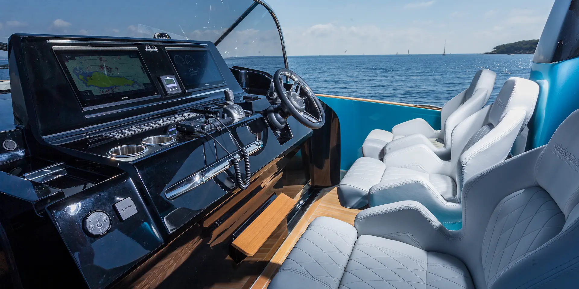 Het luxe interieur van de Solaris Power 44 Open uit 2022, met een modern stuurconsole en vier comfortabele witte stoelen aan het roer.