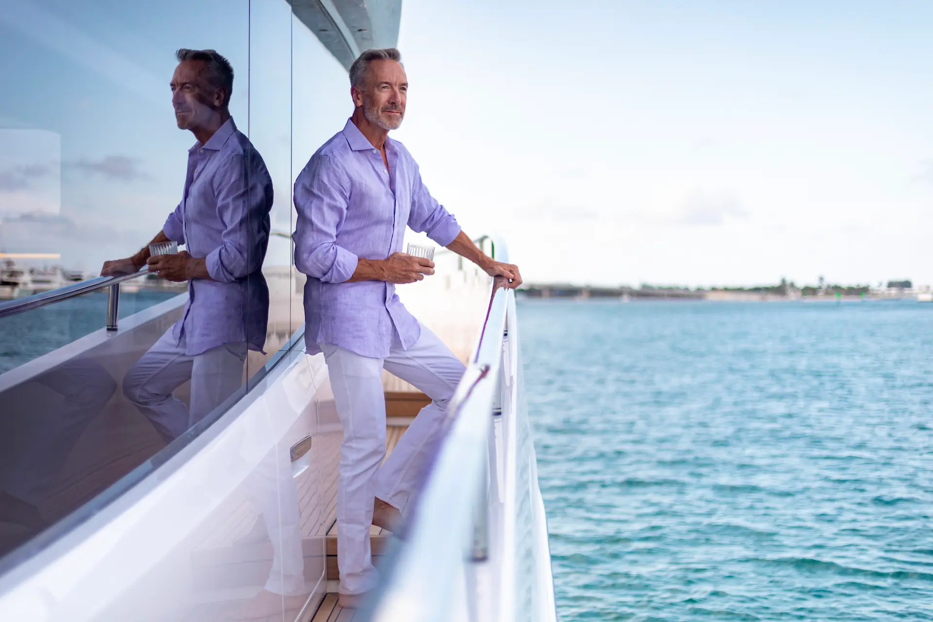 Man met een glas in de hand geniet van het uitzicht op zee vanaf het dek van een X80-jacht.